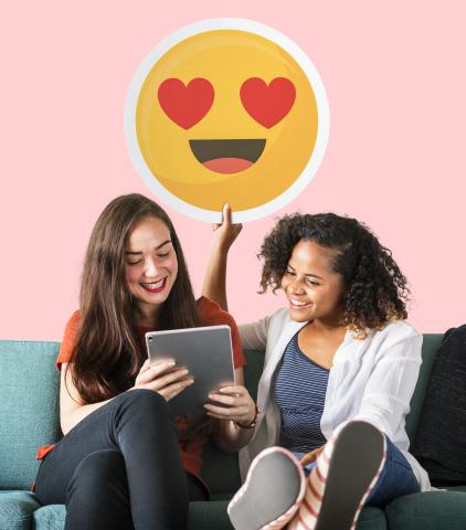 Deux jeunes femmes souriantes regardent une tablette